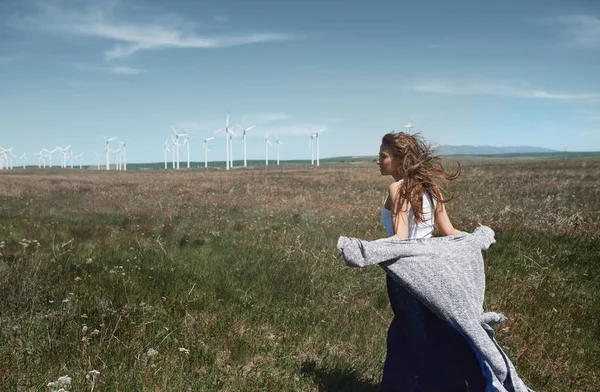 Woman with long tousled hair next to the wind turbine with the w — Stock Photo, Image