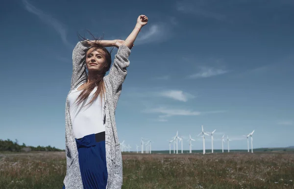 Woman with long tousled hair next to the wind turbine with the w — Stock Photo, Image
