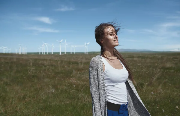 Woman with long tousled hair next to the wind turbine with the w — Stock Photo, Image