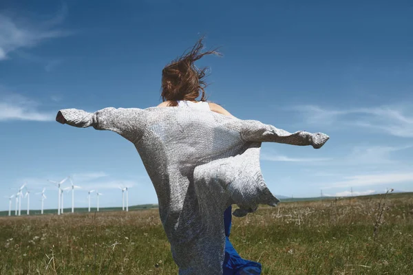 Woman with long tousled hair next to the wind turbine with the w — Stock Photo, Image