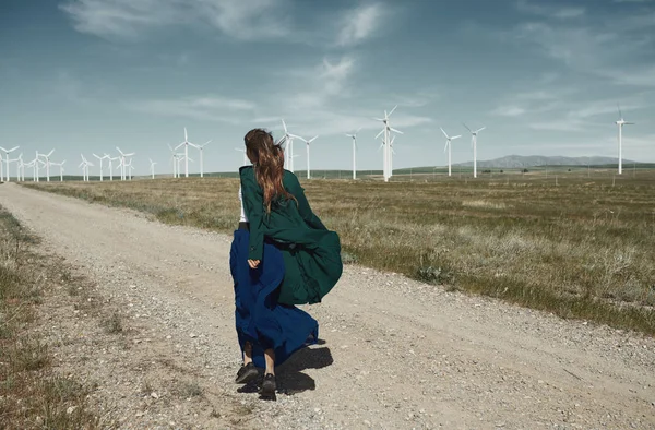 Woman with long tousled hair next to the wind turbine with the w — Stock Photo, Image