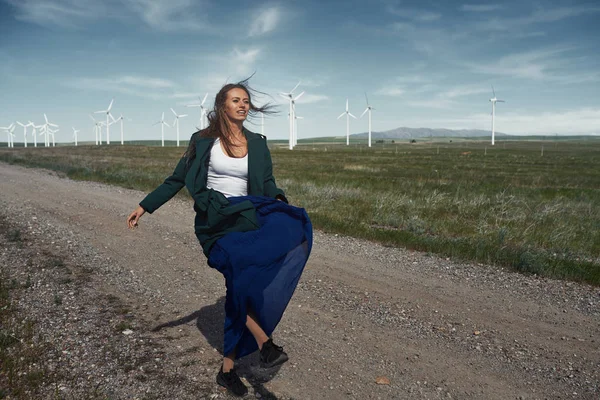 Woman with long tousled hair next to the wind turbine with the w — Stock Photo, Image