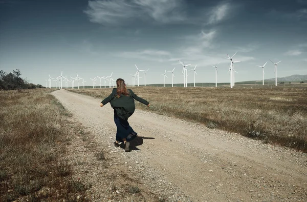 Žena s dlouhými rozcuchanými vlasy vedle větrné turbíny s w — Stock fotografie