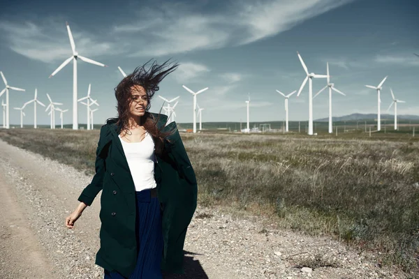 Woman with long tousled hair next to the wind turbine with the w — Stock Photo, Image