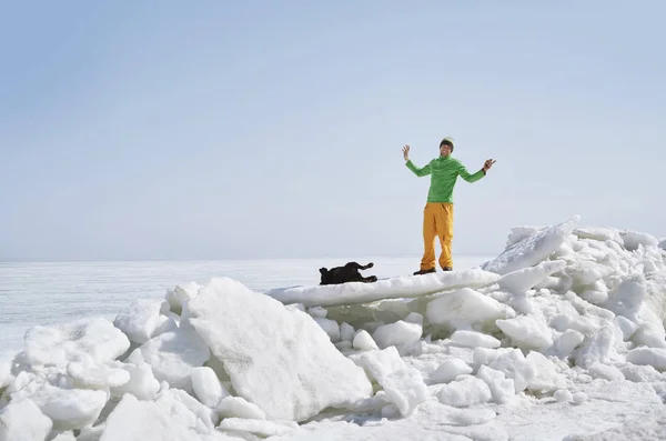 Ung vuxen man utomhus med sin hund ha kul på vintern länder — Stockfoto