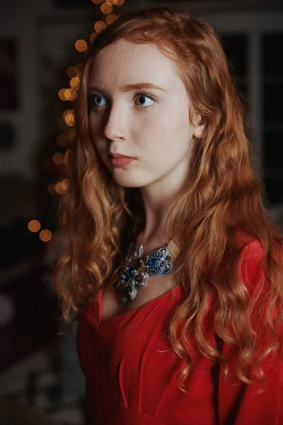 Adolescente rossa in un abito rosso e una collana ornata — Foto Stock