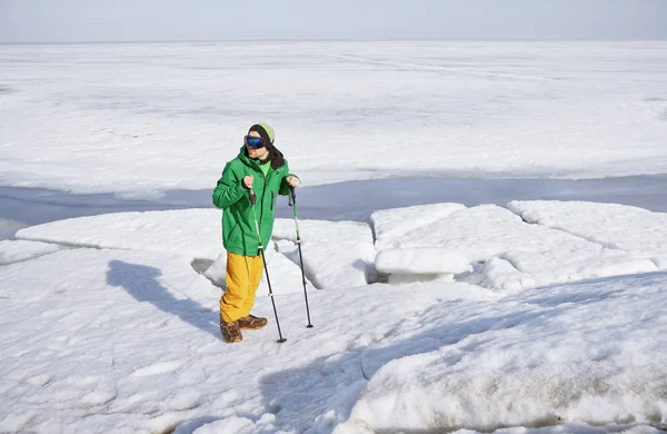 Young adult man with walking sticks outdoors exploring icy lands — ストック写真