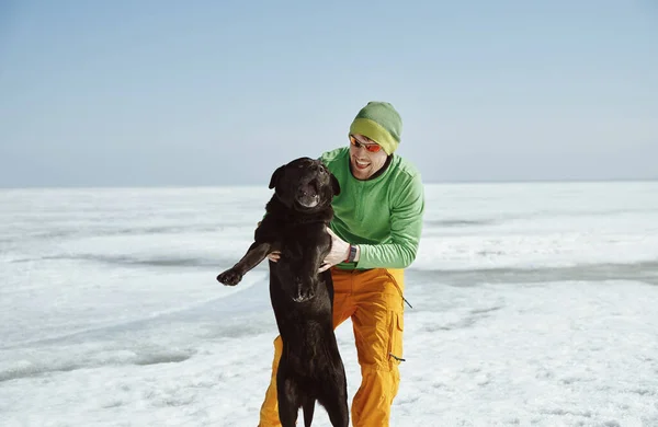 Genç Yetişkin Bir Adam Köpeğiyle Birlikte Kış Manzarasında Eğleniyor — Stok fotoğraf