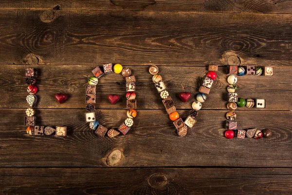 Love Woord Gerangschikt Met Pralines Houten Plank Achtergrond — Stockfoto