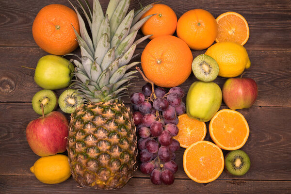 Tasty fruit background with orange, kiwi, grape, apples and lemon on the wooden table