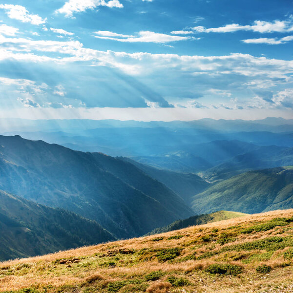Горный пейзаж с голубыми холмами и солнечными лучами
