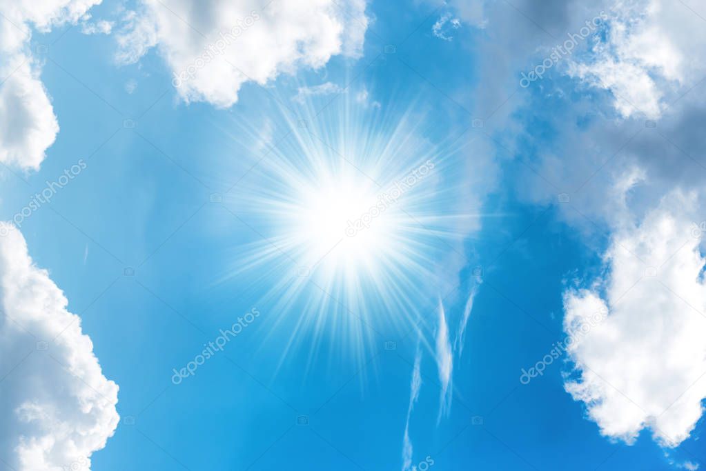 Sun with rays and white clouds on bright blue sky