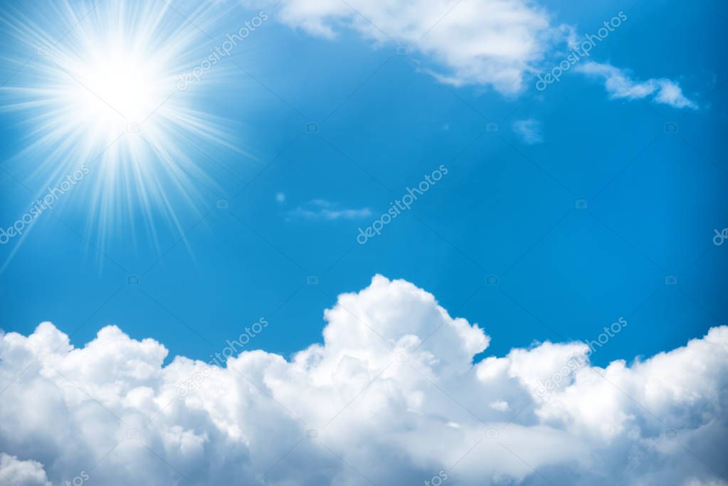 Sun with rays and white clouds on bright blue sky