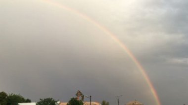 Fırtınalı gökyüzünde bulutlu renkli gökkuşağı. 4K görüntü