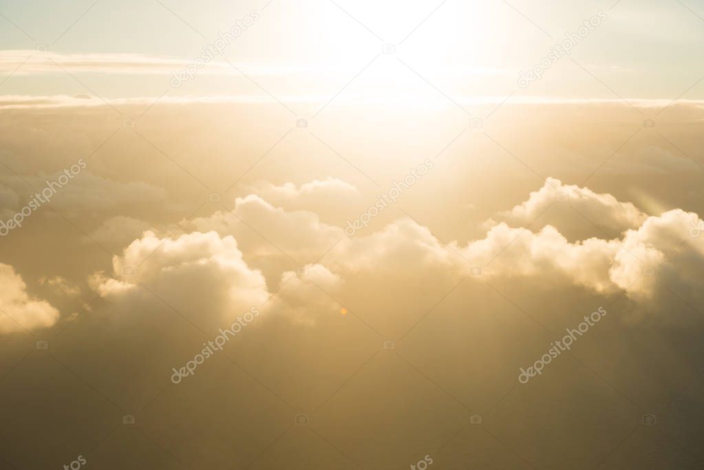 Airplane view of clouds, ocean and bright sun