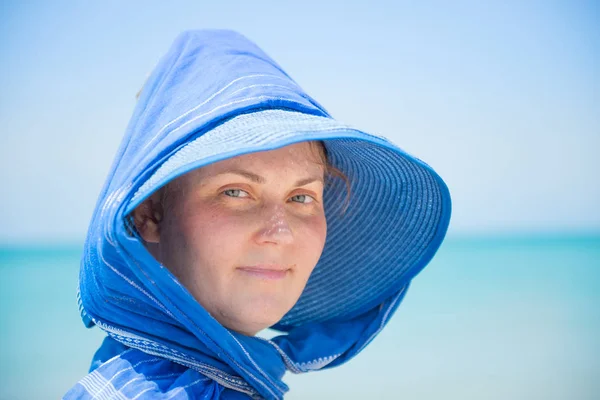 Mavi su arka planındaki şapkalı kadın. — Stok fotoğraf