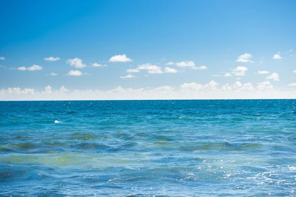 Морской пейзаж с голубой водой, небом и белыми облаками — стоковое фото