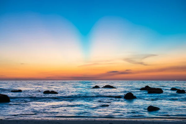 Sonnenuntergangslandschaft mit Strand, Sonne und Steinen am Meeresufer — Stockfoto