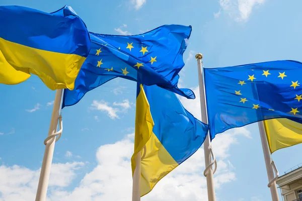 Flagpoles with European Union and Ukraine flags on blue sky back — Stock Photo, Image