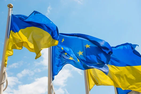 Mavi gökyüzü geri Avrupa Birliği ve Ukrayna bayrakları ile bayrak direkleri — Stok fotoğraf