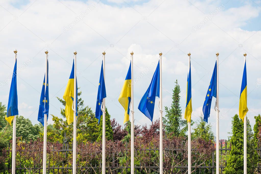 Flagpoles with European Union and Ukraine flags on blue sky back