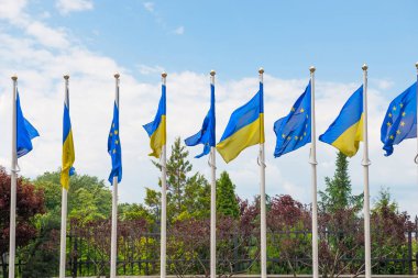 Mavi gökyüzü geri Avrupa Birliği ve Ukrayna bayrakları ile bayrak direkleri
