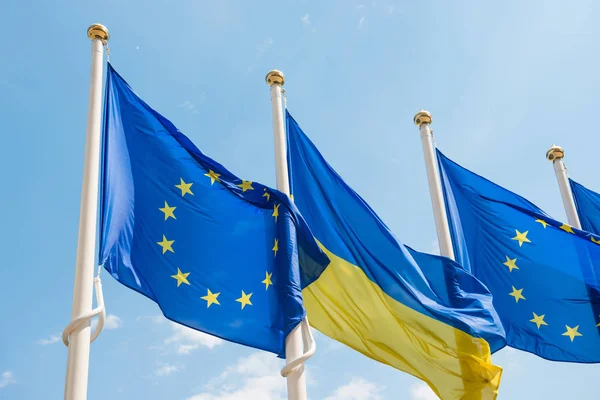 Flagpoles with European Union and Ukraine flags on blue sky back — Stock Photo, Image