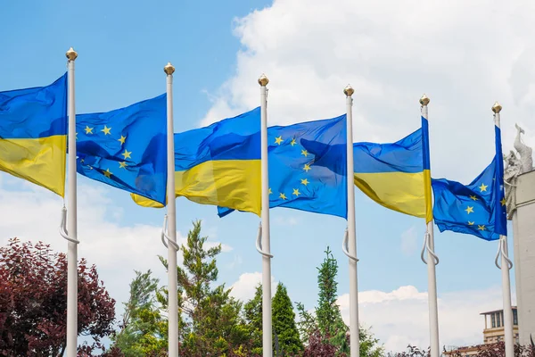 Flagpoles with European Union and Ukraine flags on blue sky back — Stock Photo, Image