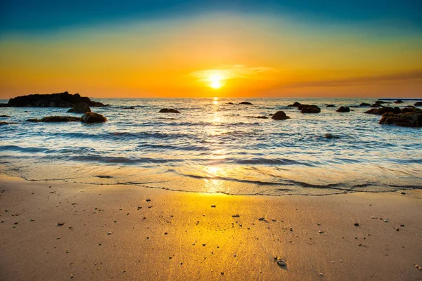 Sunset landscape with beach, sun and stones at sea shore — Stock Photo, Image