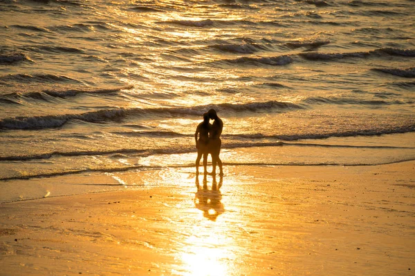 Silhouetten von Menschen am Strand bei Sonnenuntergang — Stockfoto