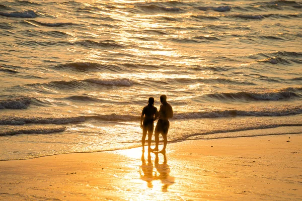Silhouettes of people on beach at sunset — Stock Photo, Image
