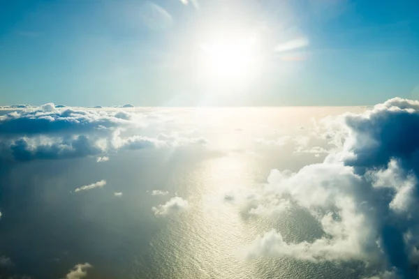 Flygplan vy över molnen, ocean och ljusa solen — Stockfoto