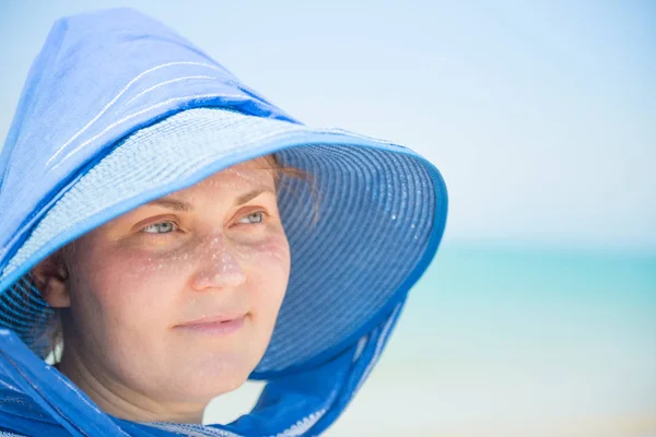 Mavi su arka planındaki şapkalı kadın. — Stok fotoğraf