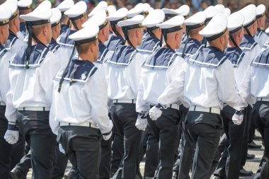 Beyaz üniformalı askerler askeri geçit törenine yürüyorlar.