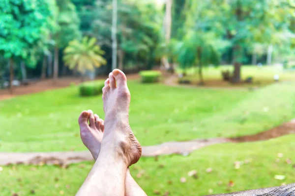 Bare feet of resting man on green lawn background. Erawan National park, Thailand. Relax lifestyle concept