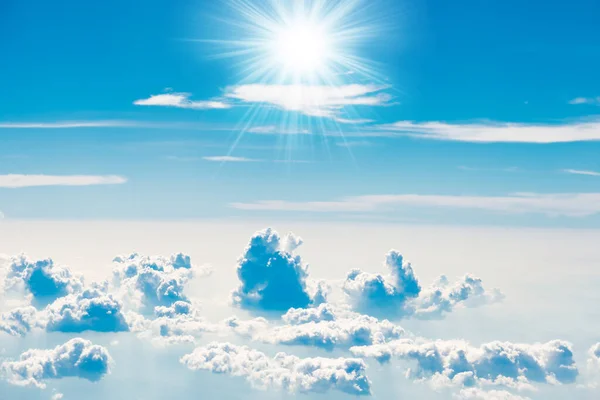 Blue sky with white clouds and shining sun rays, above aerial view from a plane, nature blue sky background