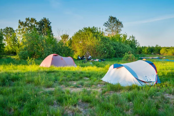 テントキャンプは森の緑の草原の日没時にキャンプ場と — ストック写真