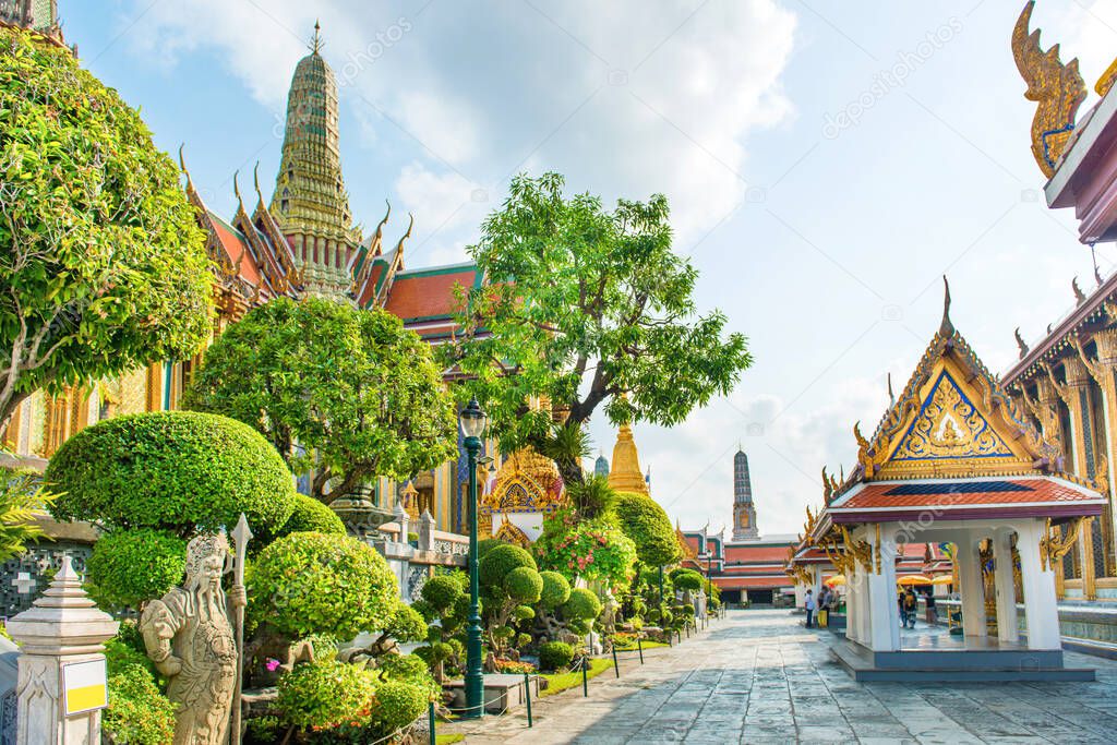 View of inner court of Temple of Emerald Buddha with ornate buildings and trees. Grand Palace complex, Bangkok, Thailand