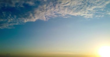 Gün batımı gökyüzü ve bulutlar hareket eden güneşle birlikte mavi arka planda yer alıyor. Zaman Ayarı 4K şarjörü