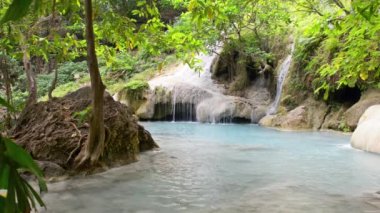 Yeşil tropikal ormandaki mavi göle şelale şelalesi düşüyor. 4K video klibi