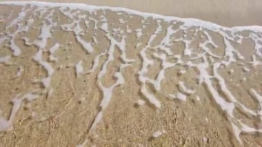 Sarı kumsalda deniz dalgası, havadan yakın çekim 4K video