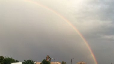 Fırtınalı gökyüzünde bulutlu renkli gökkuşağı. 4K görüntü