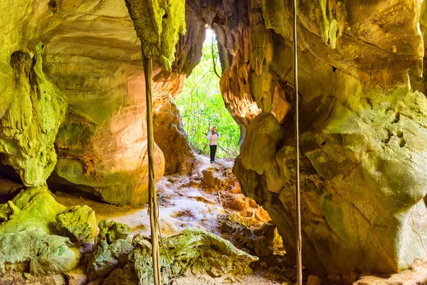 洞窟の中の女性のシルエットとジャングルの森からの太陽の光 — ストック写真