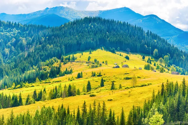 青い山の上に小さな田舎の家や森と日当たりの良い牧草地 — ストック写真
