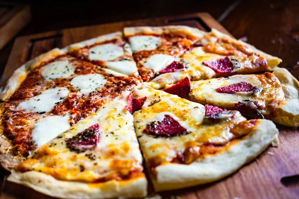 Italiaanse Pizza Plakjes Donkere Houten Snijplank Met Kopie Ruimte — Stockfoto