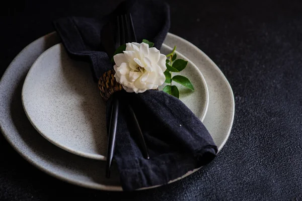 コピースペース付きブラックストーンテーブルの上に白いバラの花で飾られた現代の石器や刃物でミニマリズムテーブル設定 — ストック写真