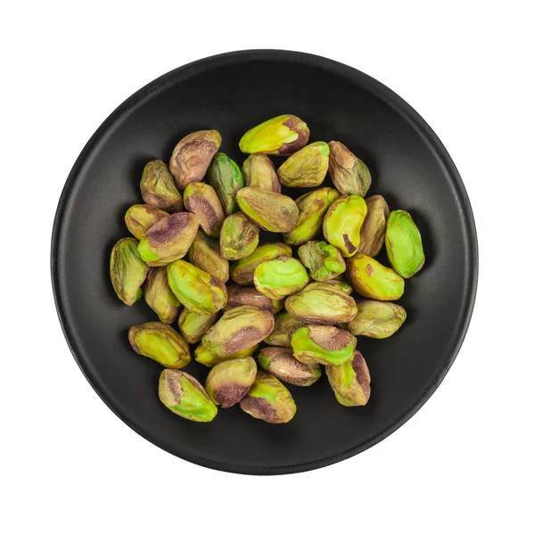 Pistachos en una placa negra aislados sobre fondo blanco . — Foto de Stock