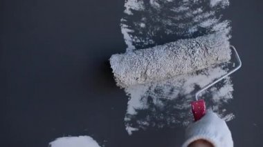 Genç işçi odada duvar boyama. Elinde boya rulosu