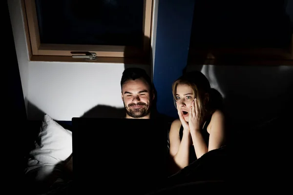 Young couple with laptop watching movie in bed — Stock Photo, Image