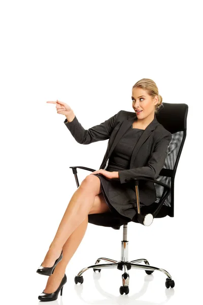 Geschäftsfrau sitzt auf einem Stuhl und zeigt leeren Raum — Stockfoto